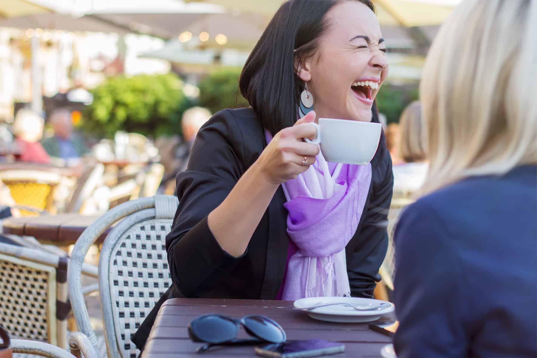 Young cheerful woman laughing while chatting with friend