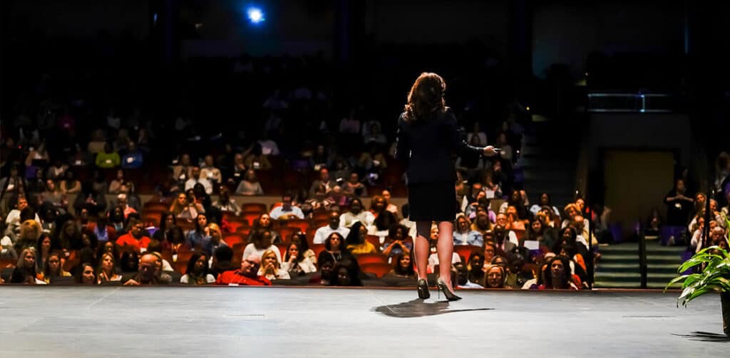 Joyce speaking from a stage to an audience in Alabama