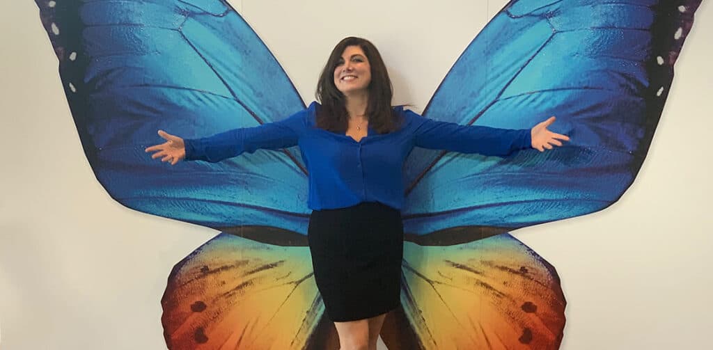 Joyce posing in front of a big painting of a butterfly